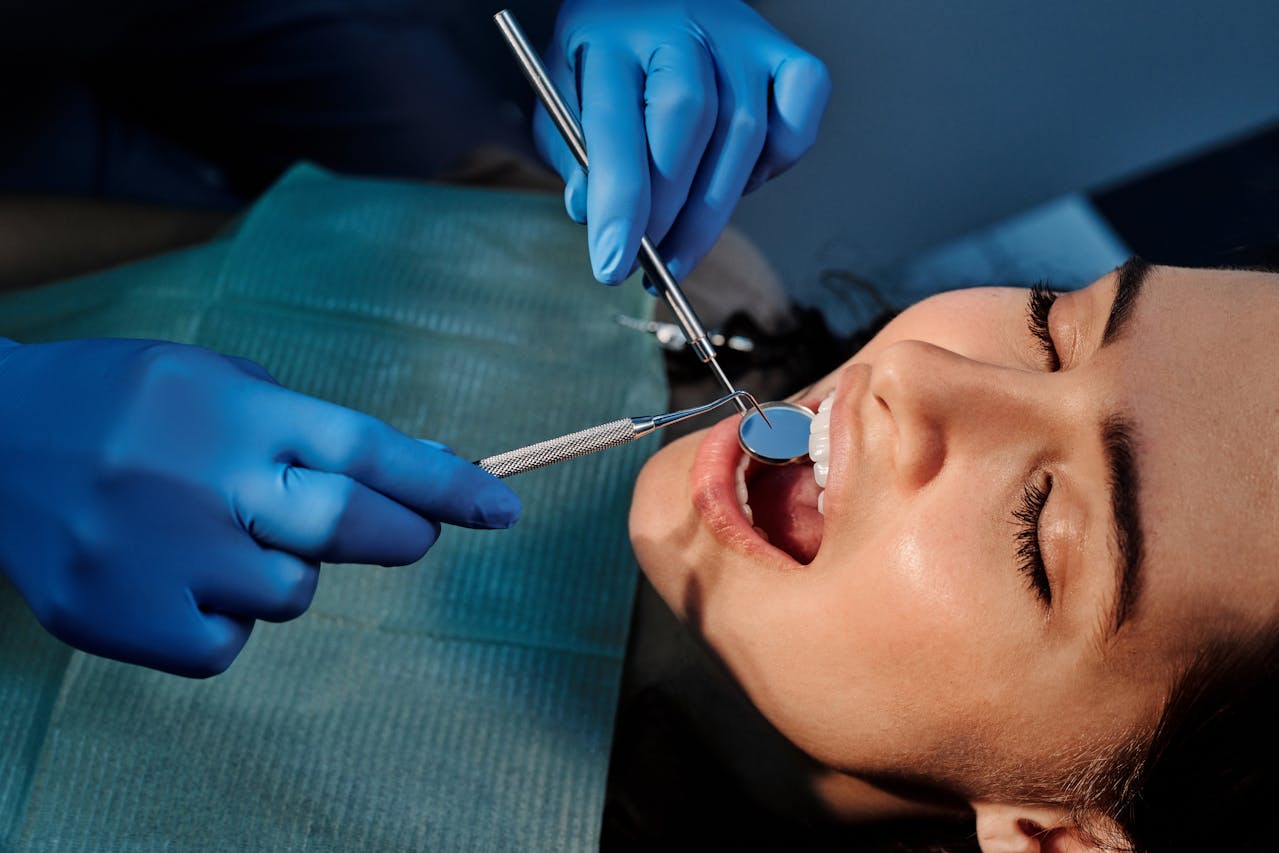 Dentist checking patient’s smile with mirror explaining teeth implants cost in Melbourne